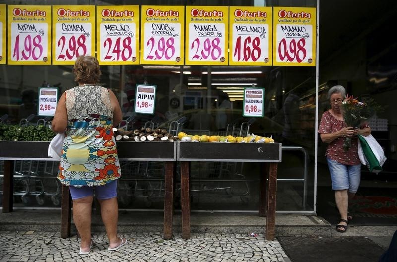 © Reuters. A woman looks on prices at a food market in Rio de Janeiro