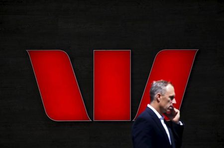 © Reuters. A man talks on his mobile phone in front of a Westpac Bank logo in central Sydney, Australia