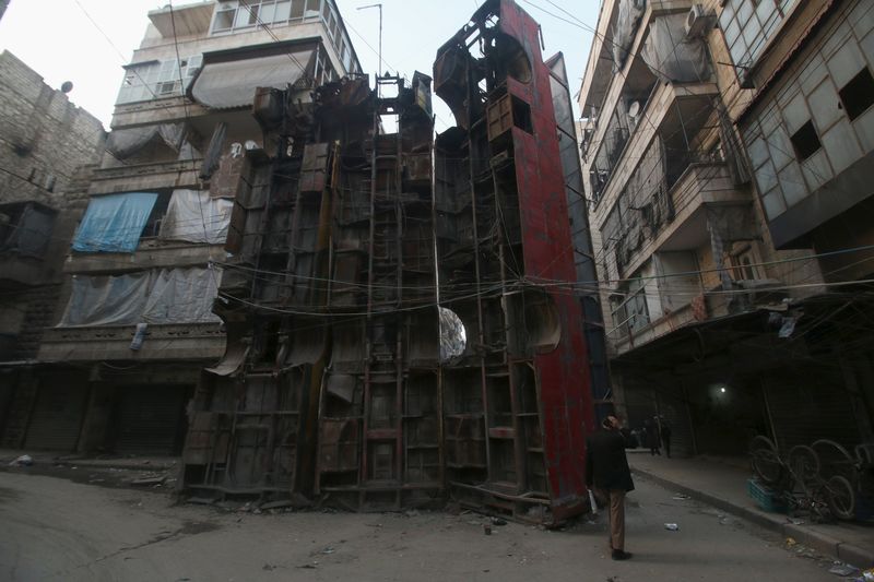 © Reuters. Civilians walk near upright buses barricading a street, in Aleppo's rebel-controlled Bustan al-Qasr neighbourhood