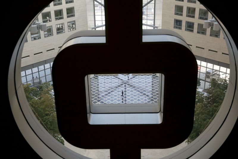© Reuters. A man speaking on the phone is seen through the logo of the Bank of China at its head office building in Beijing