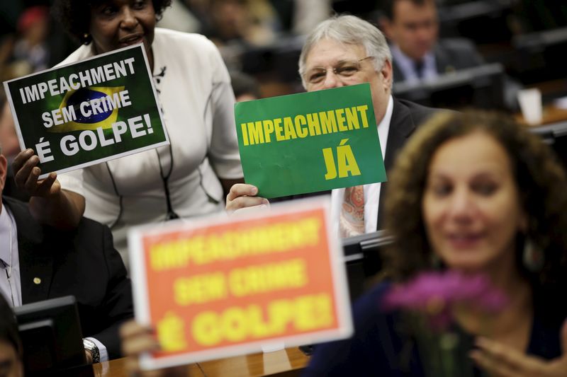 © Reuters. Congressmen hold signs during a session of the impeachment committee of Brazil's President Dilma Rousseff, in Brasilia