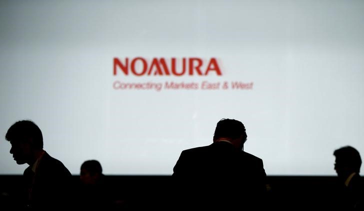 © Reuters. Силуэты инвесторов на фоне логотипа Nomura Holdings во время инвестиционного форума в Токио в 2015 году 