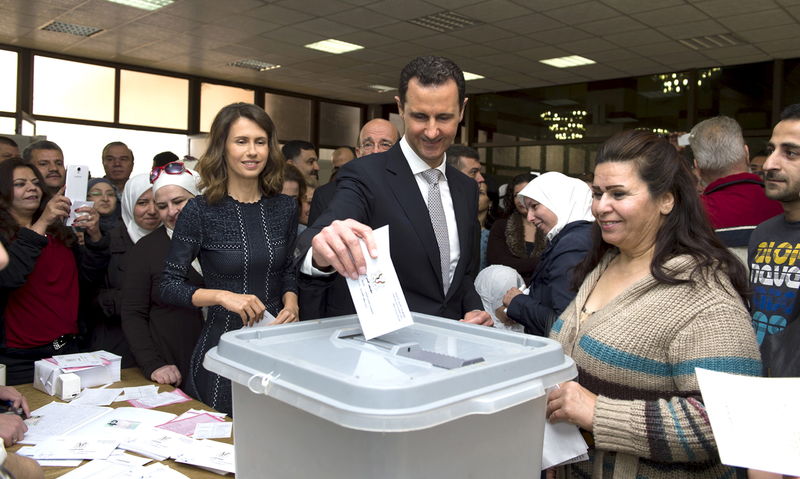 © Reuters. Syria's President Bashar al-Assad casts his vote next to his wife Asma inside a polling station during the parliamentary elections in Damascus