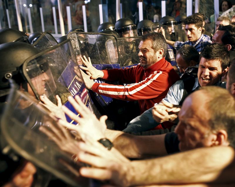 © Reuters. Protestors clash with policemen in front of ruling party VMRO headquarters in Skopje