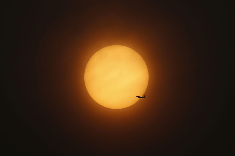 © Reuters. An aeroplane flies past the setting sun near Hongqiao International Airport in Shanghai