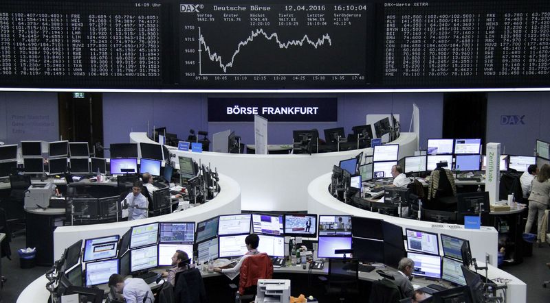 © Reuters. Traders work at their desks in front of the German share price index, DAX board, at the stock exchange in Frankfurt