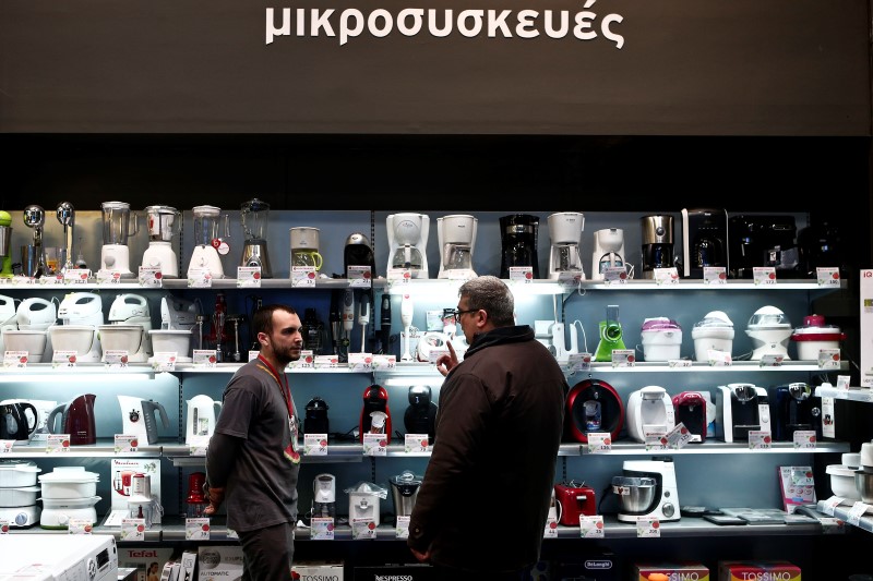 © Reuters. Employee of Electroniki retail chain Stamatis Kyriakos listens to a customer at an Electroniki shop in Athens