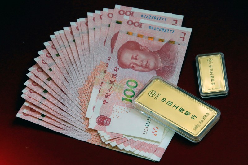 © Reuters. ICBC Bank's gold products are pictured with Chinese 100 yuan banknotes in this illustration photo