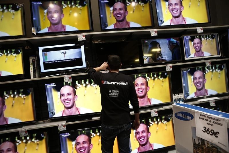 © Reuters. Employee of Electroniki retail chain Yannis Papageorgiou sets a television at an Electroniki shop in Athens