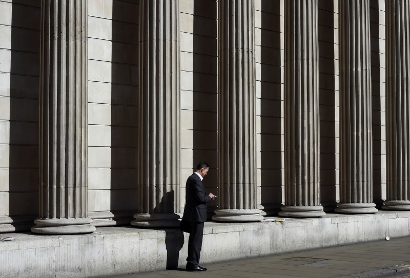 © Reuters. A City worker views his phone outside of the Bank of England in the City of London, Britain