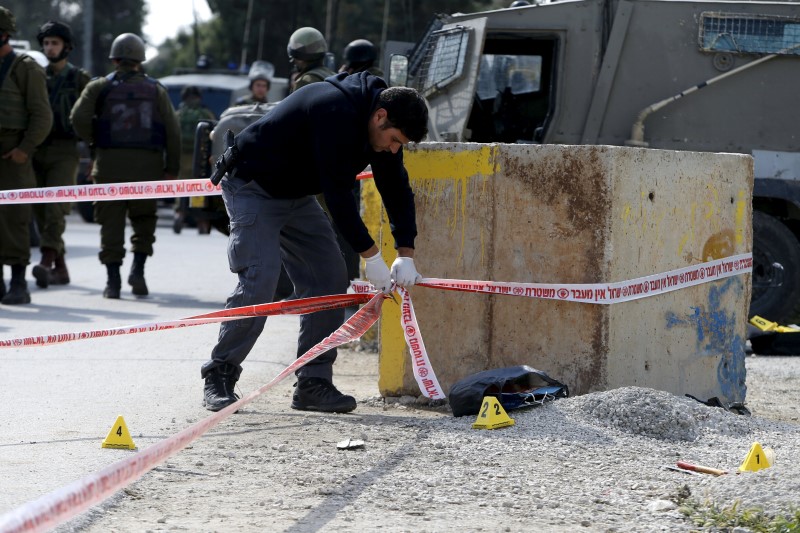 © Reuters. Israeli forces inspect the scene where a Palestinian, whom the Israeli military said attacked Israeli soldiers with an axe, was shot dead north of the West Bank city of Hebron 