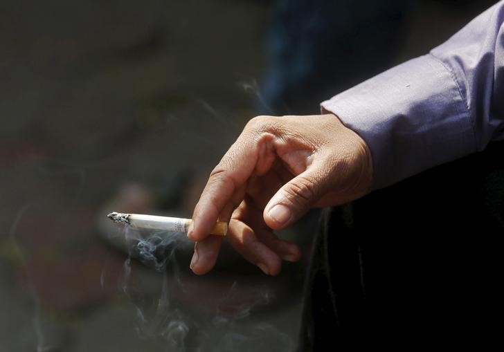 © Reuters. A man smokes a cigarette along a road in Mumbai, India