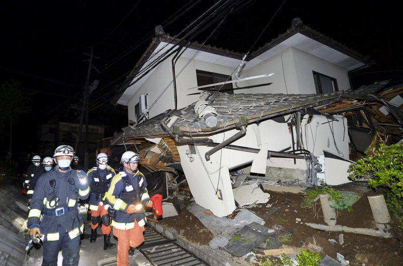 © Reuters. Bombeiros vistos ao lado de casa destruída por terremoto no Japão