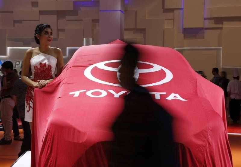 © Reuters. A model stands beside a veiled, new Toyota Sienta car at the Indonesian International Motor Show in Jakarta