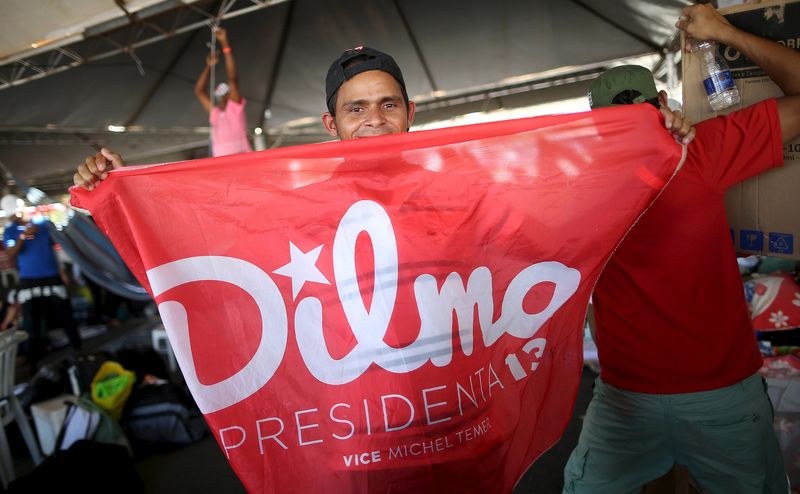 © Reuters. A member of the Landless Workers Movement (MST) shows a flag in support of Brazil's President Rousseff inside a tent at the camp, ahead of the impeachment process vote of Rousseff in the lower house in Brasilia