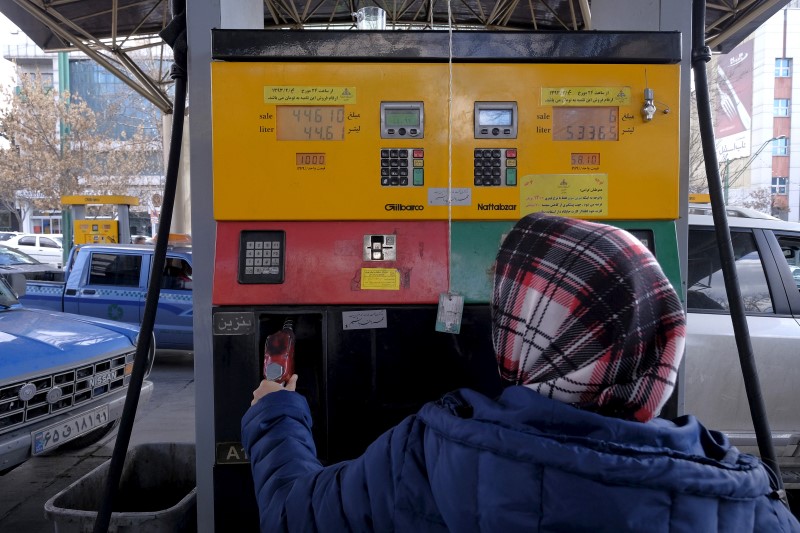 © Reuters. An Iranian woman puts a nozzle back after refuelling her car at a petrol station in Tehran