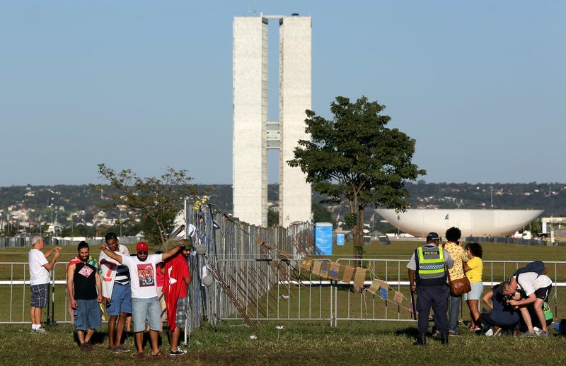 © Reuters. Pessoas tiram fotos em muro erguido na Esplanada dos Ministérios para separar manifestantes favoráveis e contrários ao impeachment da presidente Dilma Rousseff.