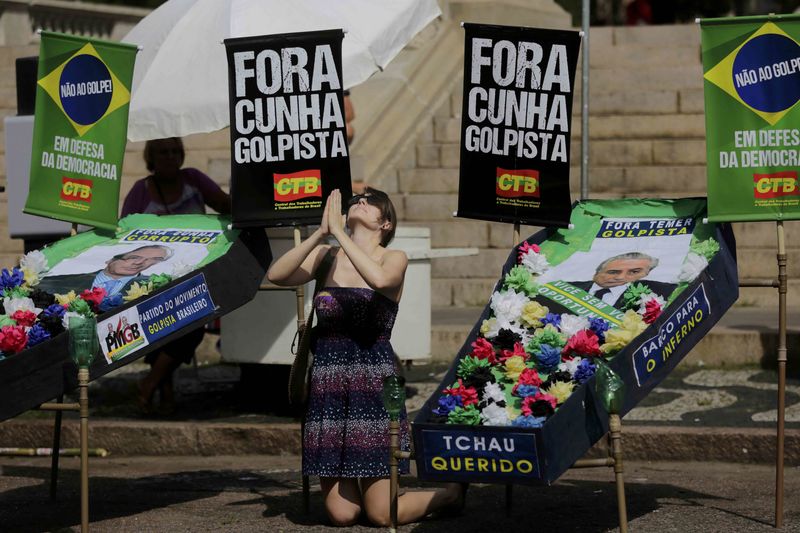 © Reuters. A supporter of President Dilma Rousseff kneels and gestures between mock coffins in Porto Alegre