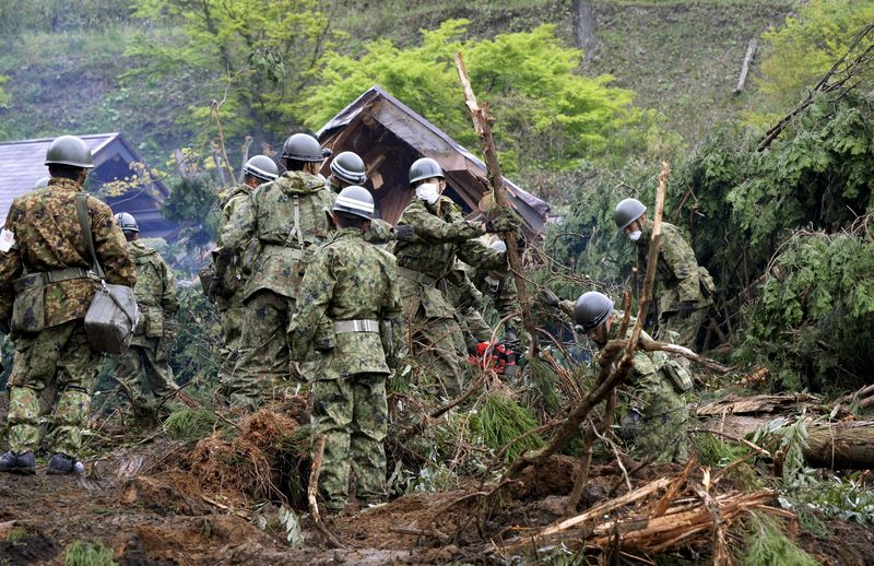 © Reuters. Japan Ground Self-Defense Force soldiers conduct search and rescue operations for a missing guest at a destroyed mountain villa following a landslide site caused by an earthquake in Kumamoto