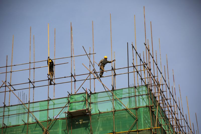 © Reuters. Labourers work on a scaffolding of a construction site at an industrial zone in Beijing