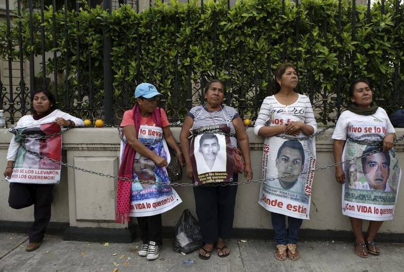 © Reuters. Relatives hold pictures of some of the 43 missing students of Ayotzinapa College Raul Isidro Burgos, as they chain themselves to a fence during a protest to demand justice for the missing students, outside the Interior Ministry in Mexico City, Mexico