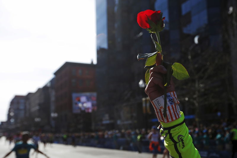 © Reuters. A runner holds up a rose as she finish the 120th running of the Boston Marathon in Boston, Massachusetts 