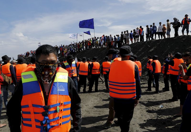 © Reuters. File photo shows security guards watching as fishermen stand on top of reclaimed land during a protest against land reclamation in Jakarta Bay