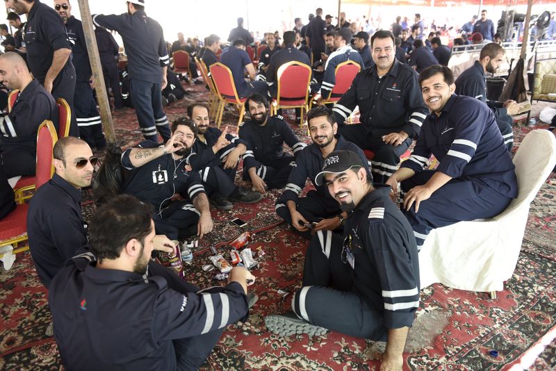 © Reuters. Kuwaiti oil sector employees sit in a shaded area on the first day of an official strike called by the Oil and Petrochemical Industries Workers Union over public sector pay reforms, in Ahmadi