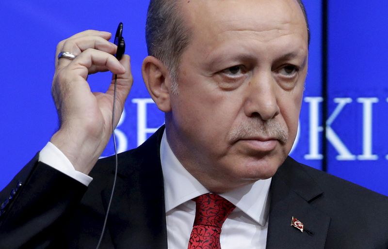 © Reuters. Turkish President Tayyip Erdogan removes his ear piece at the Brookings Institute in Washington