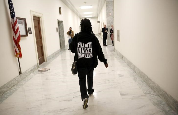 © Reuters. A woman with a "Flint Lives Matter" shirt walks toward a hearing room where Michigan Governor Rick Snyder and EPA Administrator Gina McCarthy will testify on Capitol Hill in Washington