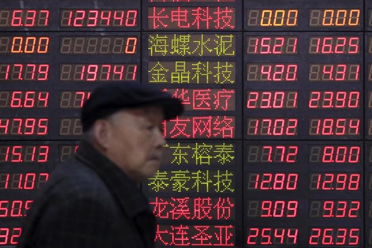 © Reuters. An investor walks past an electronic board showing stock information at a brokerage house in Shanghai