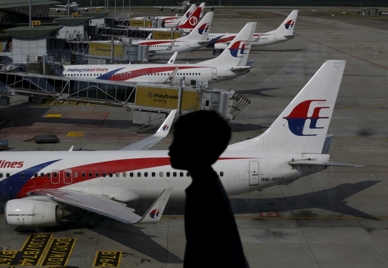 © Reuters. A boy walks past Malaysia Airlines planes on the tarmac at Kuala Lumpur International Airport in Sepang, Malaysia
