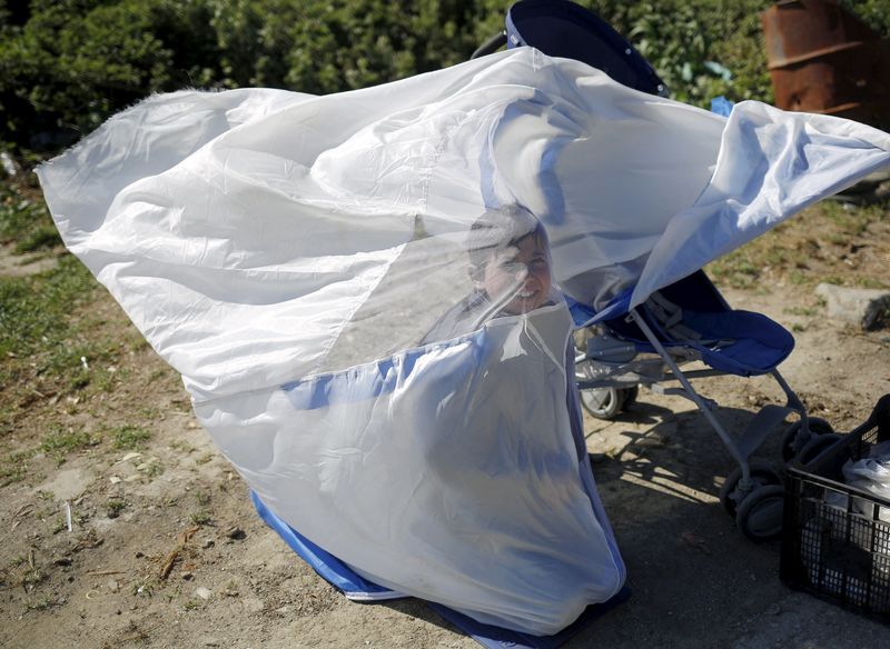 © Reuters. A boy covers himself with a net during heavy winds at a makeshift camp for migrants and refugees at the Greek-Macedonian border near the village of Idomeni