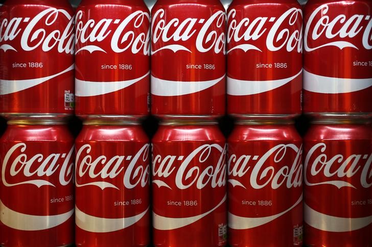 © Reuters. Cans of Coca-Cola sit on a shelf in a store in London