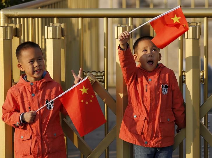 © Reuters. Twin boys Sun Qiyu and Sun Qichun hold China's national flags on the Tiananmen Gate in Beijing