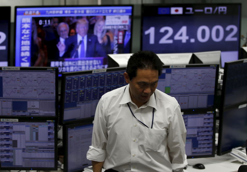 © Reuters. An employee of a foreign exchange trading company stands in front of monitors displaying Republican U.S. presidential candidate Trump on TV news and the Japanese yen's exchange rate against the euro in Tokyo