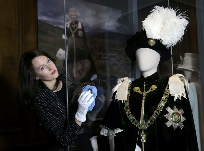 © Reuters. Gallery worker Caroline de Guitaut, curator at the royal collections trust, poses with part of the largest exhibition of The Queen's dresses and accessories ever shown in Scotland at the Palace of Holyroodhouse, Scotland