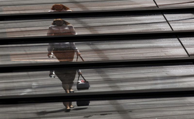 © Reuters. An office worker with a shopping bag is reflected on the roof of a building in central Sydney