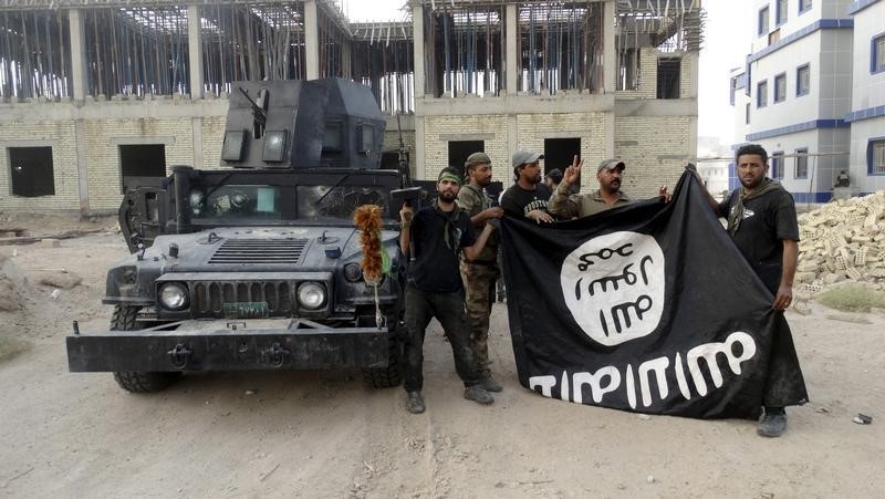 © Reuters. Iraqi security forces hold an Islamist State flag which they pulled down at the University of Anbar, in Anbar province