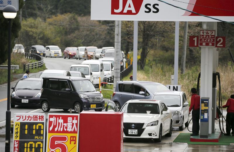 © Reuters. Cars line up while waiting to refuel at a gas station after a series of earthquakes in Aso