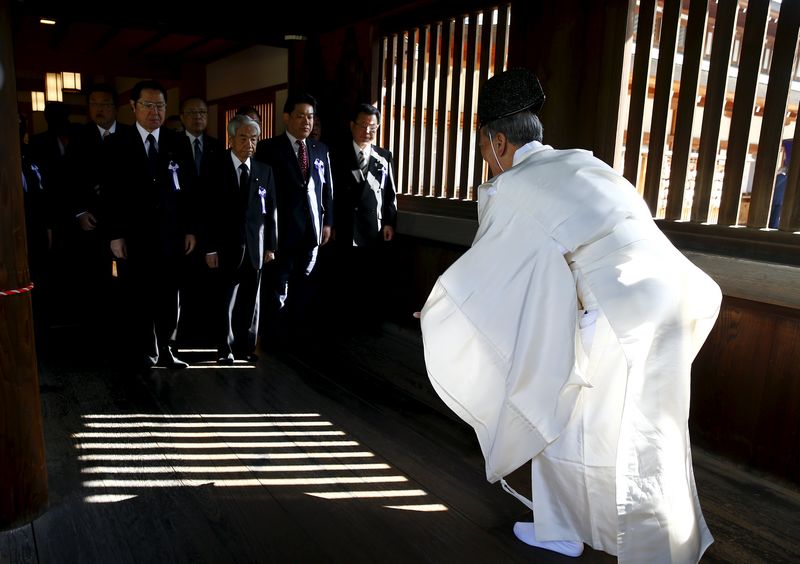 © Reuters. A Shinto priest welcomes Japanese lawmakers as they visit the Yasukuni shrine in Tokyo