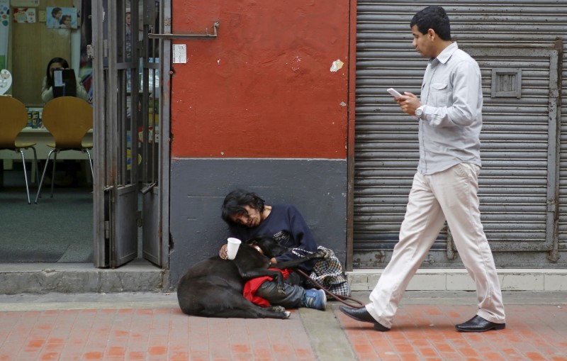 © Reuters. Arturo Tello sleeps with his dog Negrita Rubi as he asks for money in downtown Lima