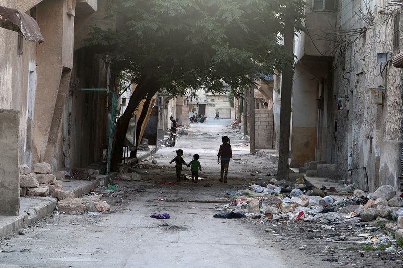 © Reuters. Children walk near garbage in al-Jazmati neighbourhood of Aleppo