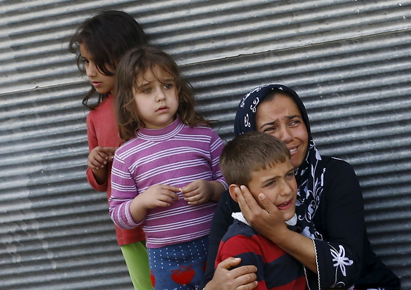 © Reuters. Una madre y sus hijos reaccionan después de que dos cohetes cayeron sobre la ciudad turca de Kilis
