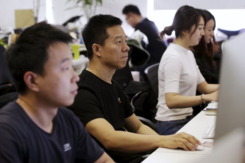 © Reuters. Jia Yueting, co-founder and head of Le Holdings Co Ltd, uses a computer on a staff's seat as he poses for a photo in Beijing