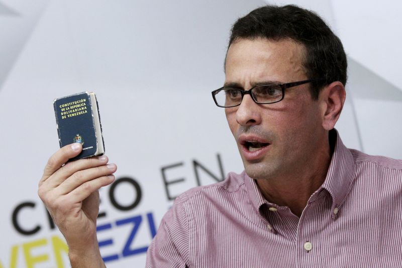 © Reuters. Líder da oposição venezuelana e governador do Estado de Miranda, Henrique Capriles,  segura um exemplar da Constituição do país enquanto fala com jornalistas em Caracas