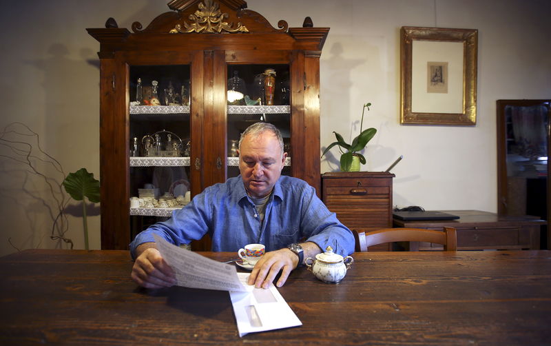 © Reuters. Domenico Bertini reads a letter from Banca Popolare di Vicenza in his house in Lonigo, near Vicenza