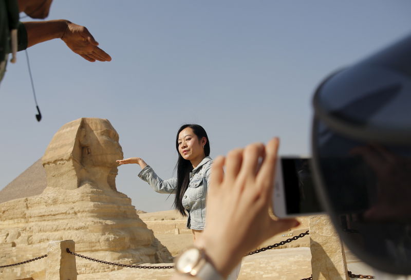 © Reuters. A Chinese tourist poses for a photo in front of the Sphinx at the Giza Pyramids on the outskirts of Cairo
