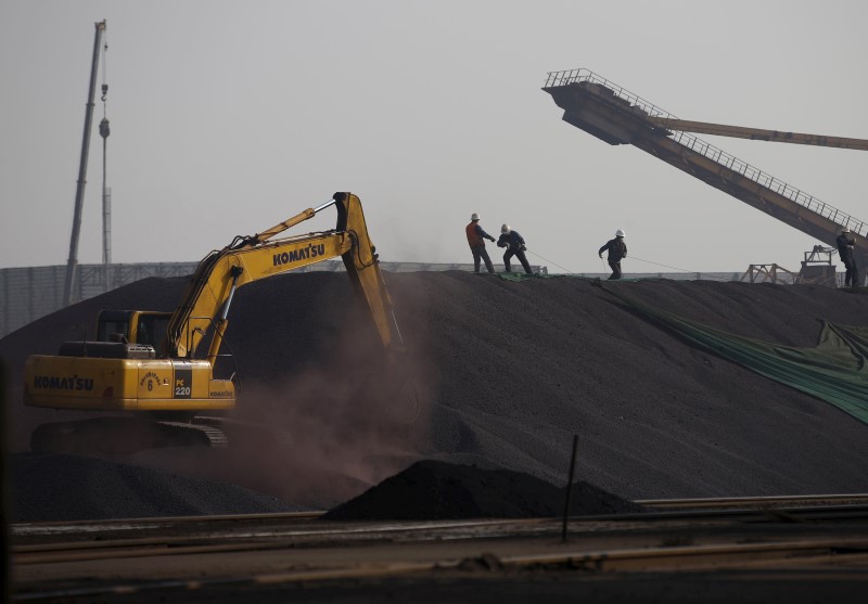 © Reuters. File picture of labourers working on a pile of iron ore at a steel factory in Tangshan