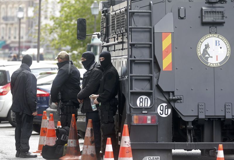 © Reuters. Members of French special police forces of Research and Intervention Brigade stand next to an armoured vehicle parked in front of the courthouse in Paris